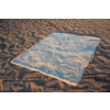 Tissu rectangulaire de couleur claire étalé sur du sable ondulé