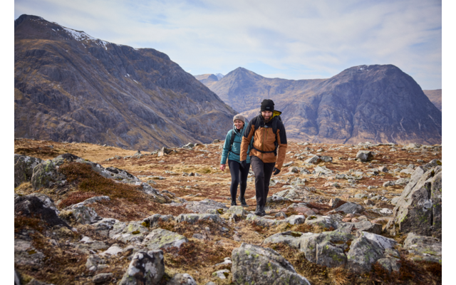 Zwei Wanderer auf einem felsigen Bergpfad mit Bergen im Hintergrund