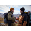 Zwei Männer mit Rucksäcken und Winterkleidung in einer Berglandschaft, die sich anlächeln