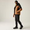 Personne portant une veste brun-noir avec intérieur de capuche jaune, bonnet noir, pantalon noir et chaussures noires, debout une main dans la poche de la veste sur fond clair
