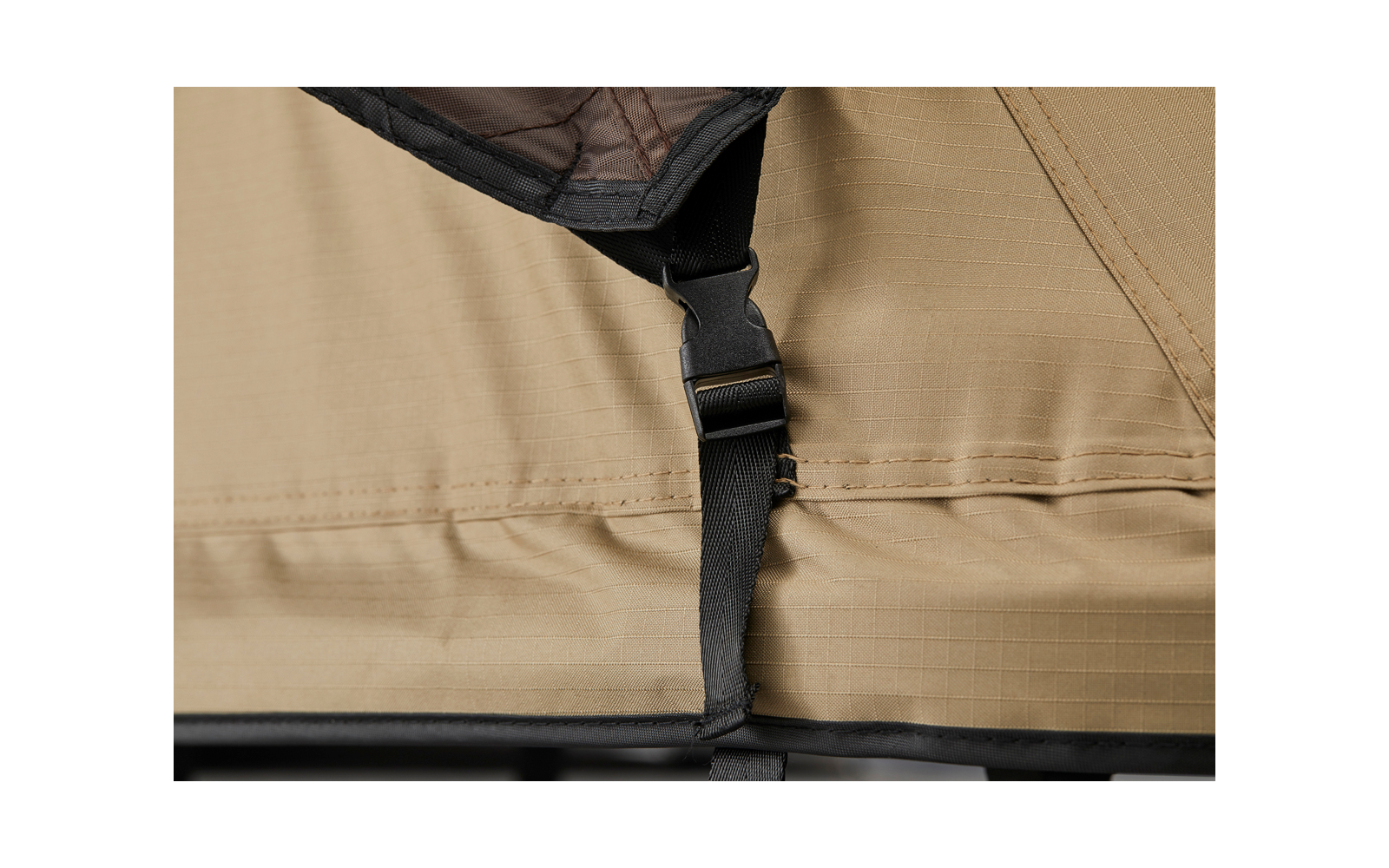 Schwarzer Nylongurt mit Kunststoffschnalle an beigefarbenem Stoff mit sichtbaren Nähten