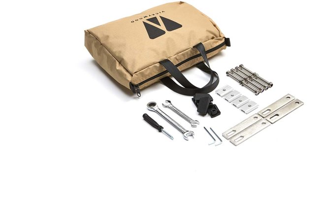 Beige Stofftasche mit schwarzen Tragegriffen und schwarzem Logo, daneben Schraubenschlüssel, Schraubendreher, Schrauben, Muttern und Metallwinkel auf weißem Hintergrund