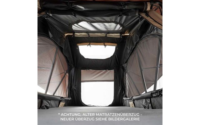 Innenansicht eines dunklen Zelts mit Matratze unten, seitlichen Mesh-Fenstern, rechteckiger Öffnung am Ende, Dachfenster und zwei Leuchten; weißer deutscher Warntext am unteren Bildrand
