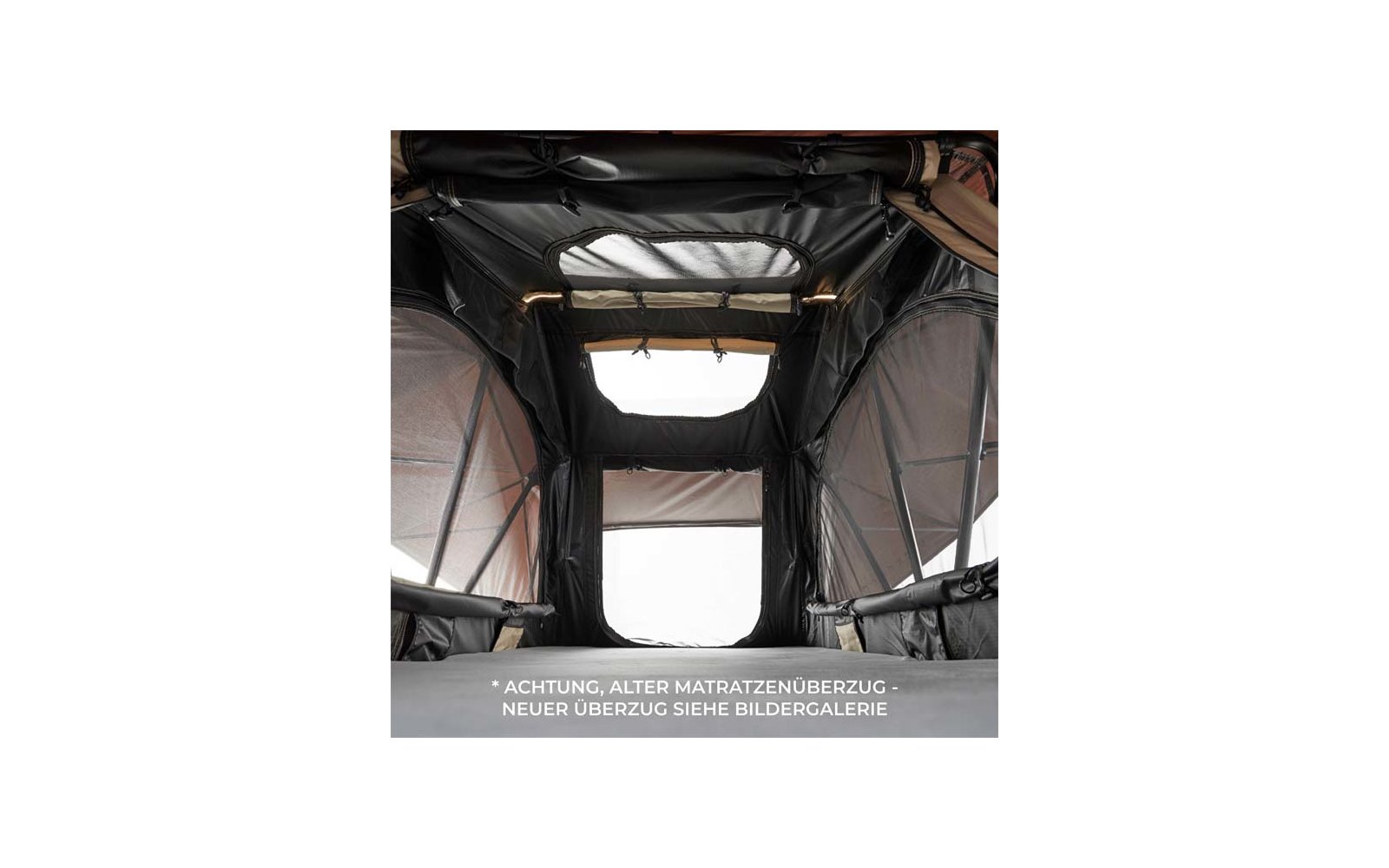 Innenansicht eines dunklen Zelts mit Matratze unten, seitlichen Mesh-Fenstern, rechteckiger Öffnung am Ende, Dachfenster und zwei Leuchten; weißer deutscher Warntext am unteren Bildrand