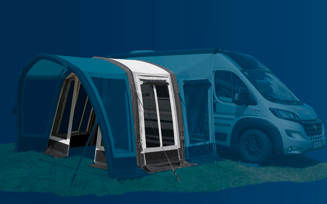 Tenda veranda blu accanto a un camper bianco su erba verde