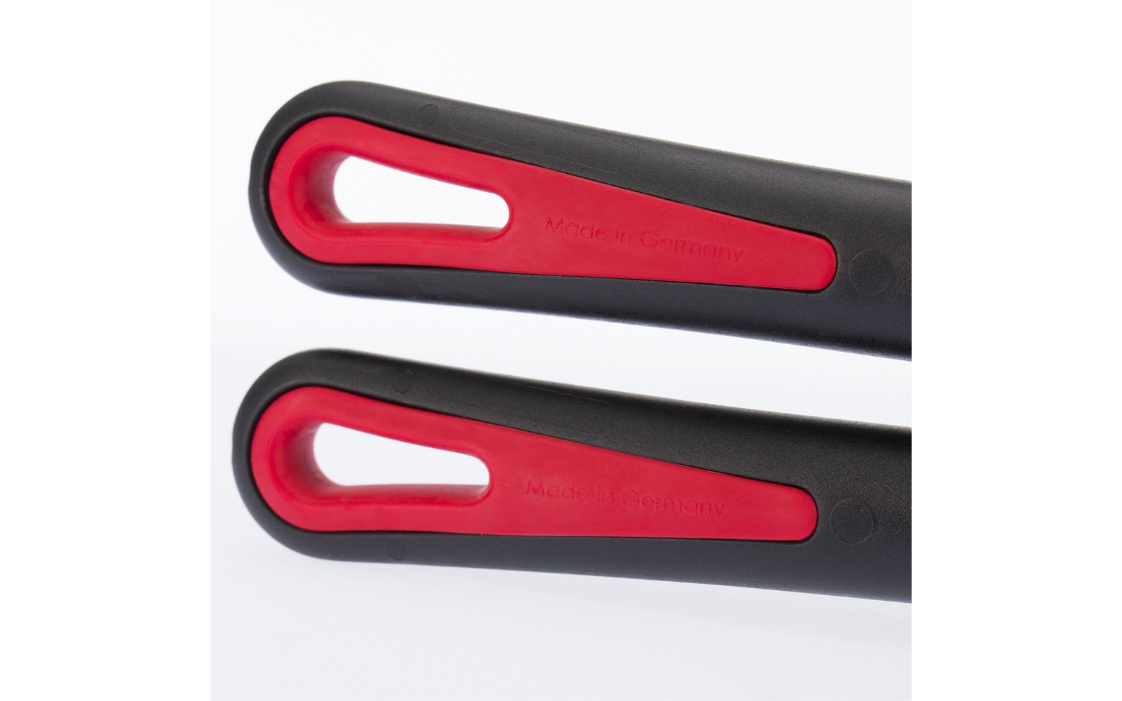 Deux poignées noires avec insert rouge et ouverture ovale allongée, 'Made in Germany' visible sur l'insert