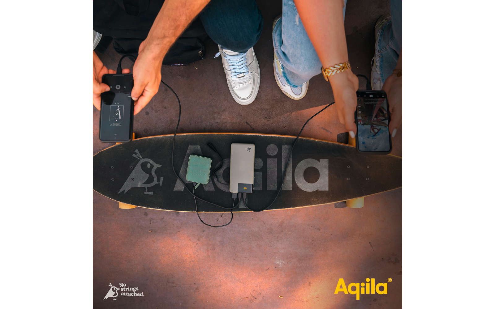 Vier Personen halten Smartphones über einem Skateboard mit verschiedenen elektronischen Geräten darauf