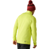 Personne de dos portant une veste jaune néon, un bonnet rouge à pompon et un pantalon foncé