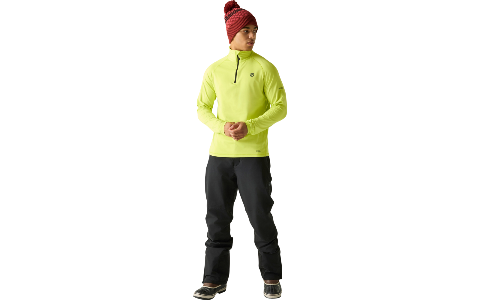 Personne debout, regarde vers la droite, porte une veste jaune fluo à demi-fermeture éclair, pantalon noir, bonnet tricot bordeaux avec pompon et bottes foncées; mains tenues devant le corps