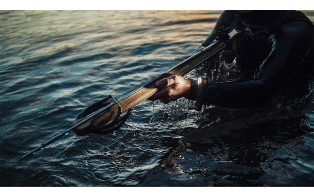 Hand, die im Wasser eine schwarze Taucherbrille hält