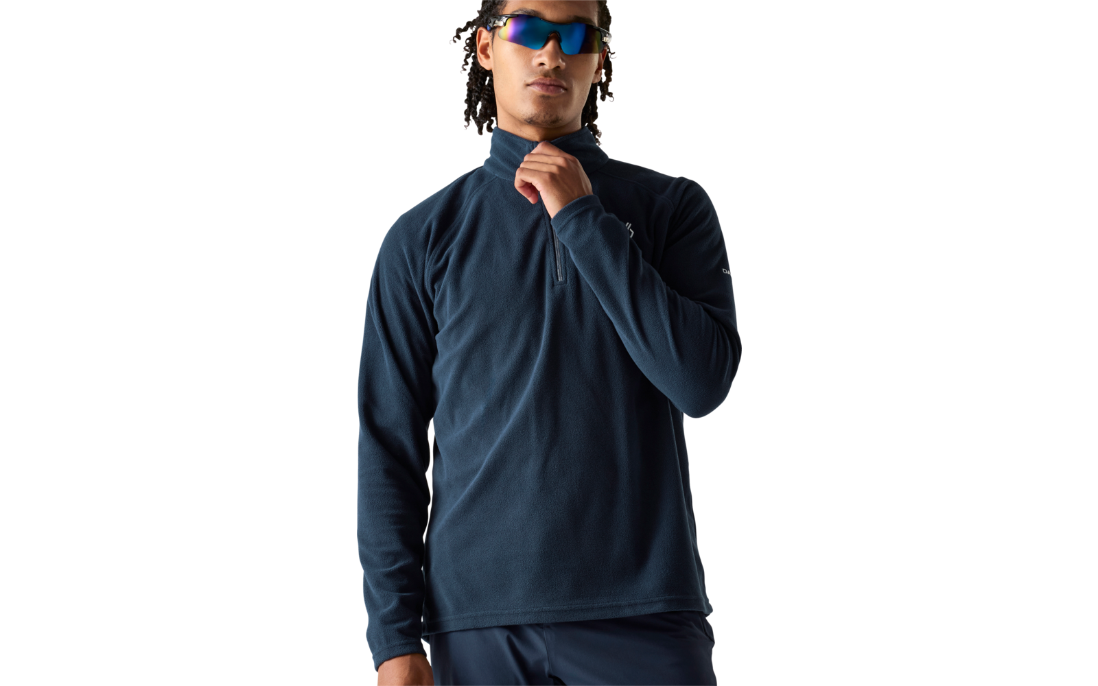 Persoon met gevlochten haar en spiegelende zonnebril, draagt donkerblauw fleece met hoge kraag en halve rits; één hand pakt de rits, witte achtergrond