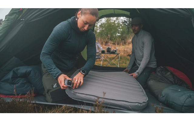 Mann macht im Zelt ein Campingbett auf