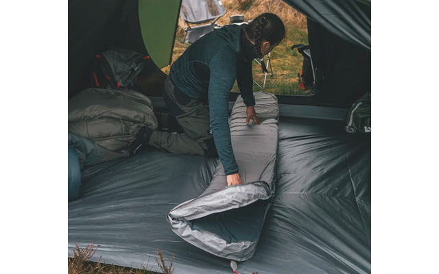Person faltet eine graue Matratze in einem Zelt zusammen