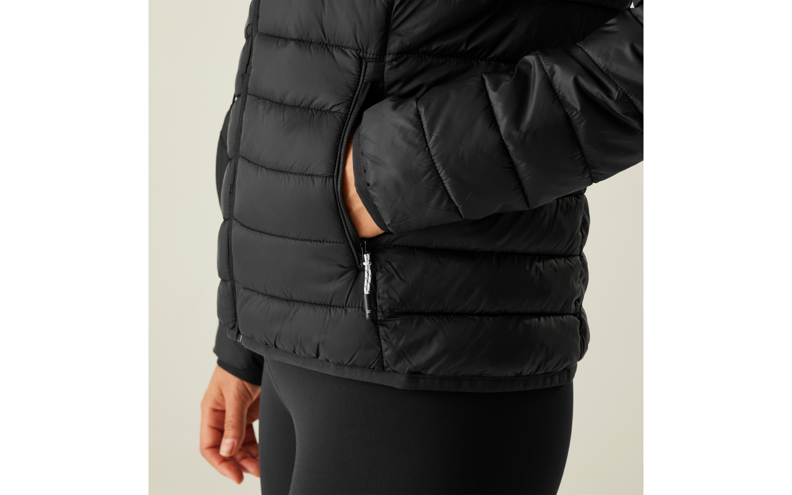 Person trägt eine schwarze gesteppte Jacke und hat eine Hand in der Hosentasche
