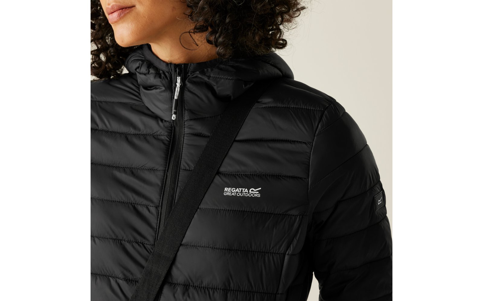 Person trägt eine schwarze Steppjacke und eine schwarze Umhängetasche