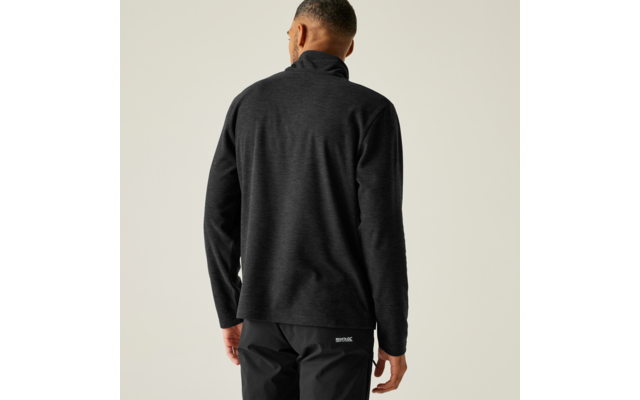 Ein Mann steht mit dem Rücken zur Kamera, trägt eine schwarze Jacke und eine schwarze Hose