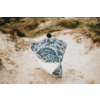 Personne avec bonnet noir, vue de dos sur des dunes de sable, enveloppée dans une grande couverture à motif bleu et blanc