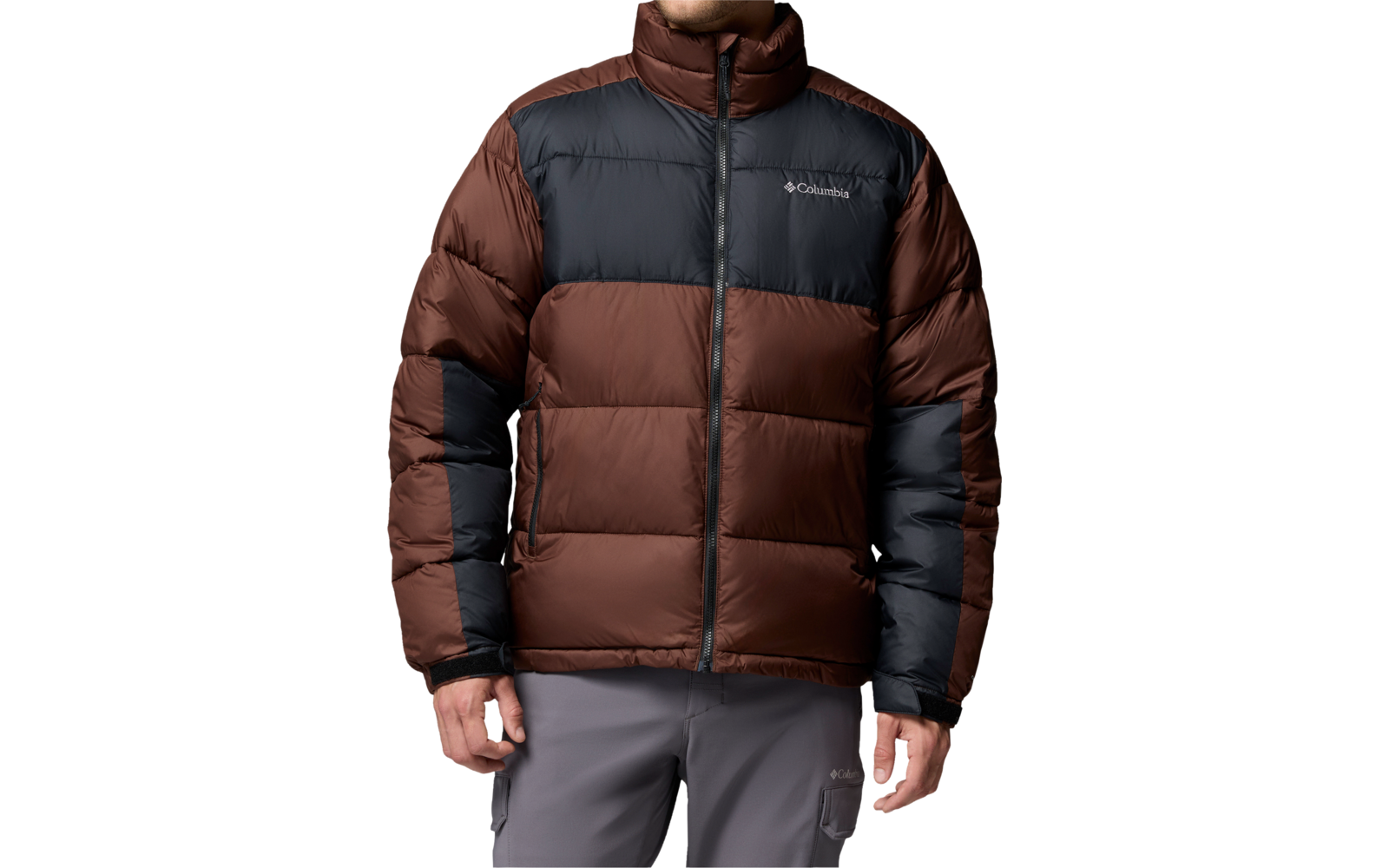 Person in braun-schwarzer Steppjacke mit Reißverschluss und sichtbarem Markenlogo, graue Hose, blickt nach rechts