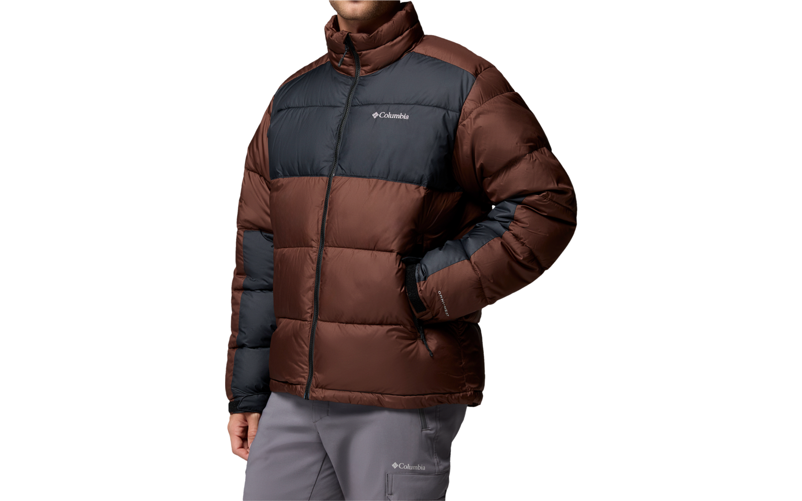 Person mit braun-dunkelgrauer Steppjacke, rechte Hand in Tasche, graue Hose, weißer Hintergrund