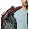 Person von Brust bis Kinn öffnet eine braune Jacke; silbernes Innenfutter und hellblaues Shirt sichtbar