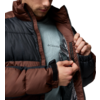 Teilansicht einer Person, die eine braun-schwarze Steppjacke öffnet; darunter ein hellblaues T-Shirt mit Columbia-Logo sichtbar