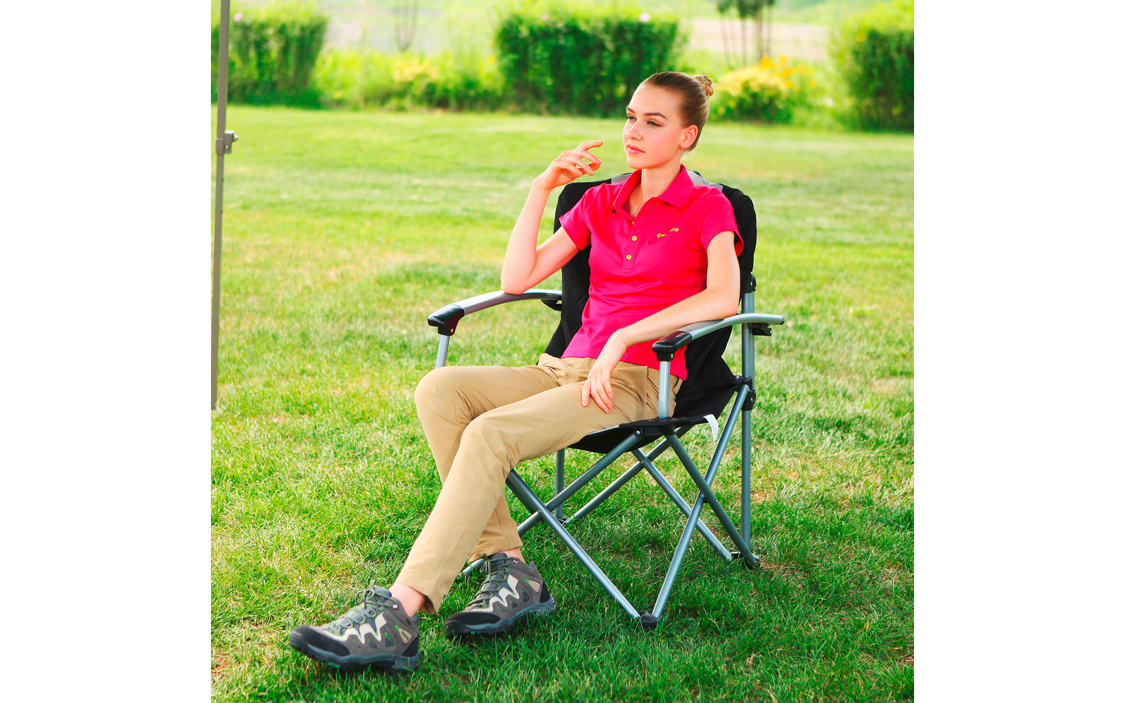 Femme en polo rouge assise sur une chaise pliante à l'extérieur
