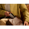 Person steckt Handy in braune Tasche