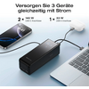 Drei elektronische Geräte werden gleichzeitig über ein schwarzes Ladegerät mit Kabeln an eine Laptop Tastatur angeschlossen
