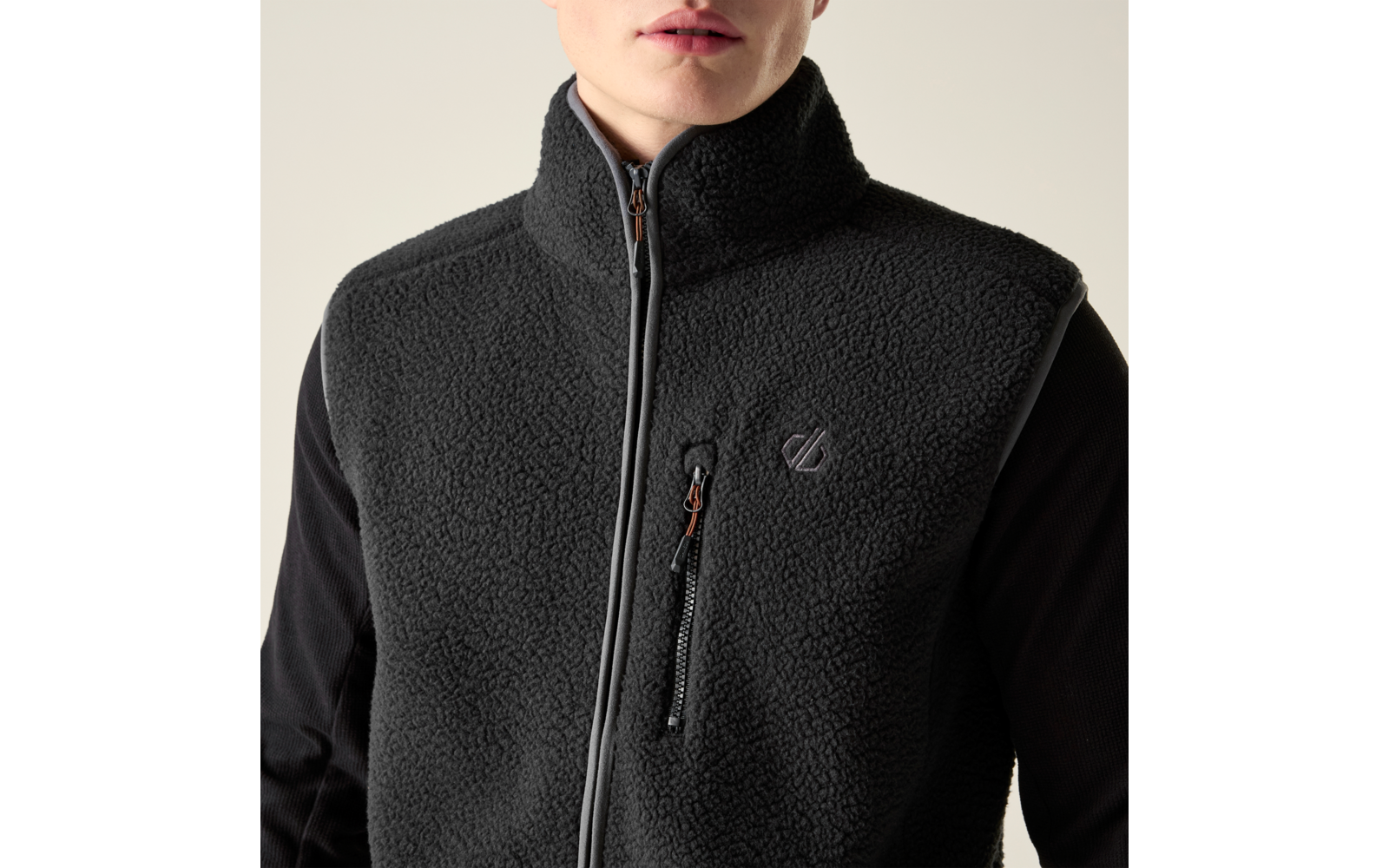 Oberkörper einer Person mit schwarzer Fleeceweste, hohem Kragen, durchgehendem Reißverschluss, schräger Brusttasche mit Reißverschluss und kleinem aufgesticktem Logo