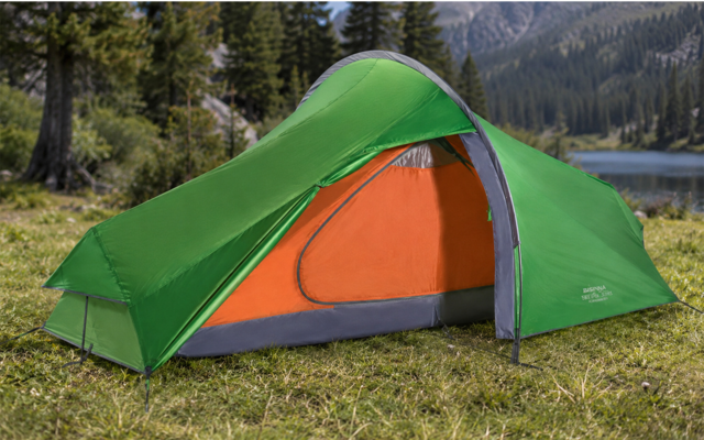 Groene tent met open oranje binnenzijde op gras; op de achtergrond bomen, een meer en bergen