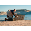 Person sitzt auf dem Boden am Strand und hält ein Tablett