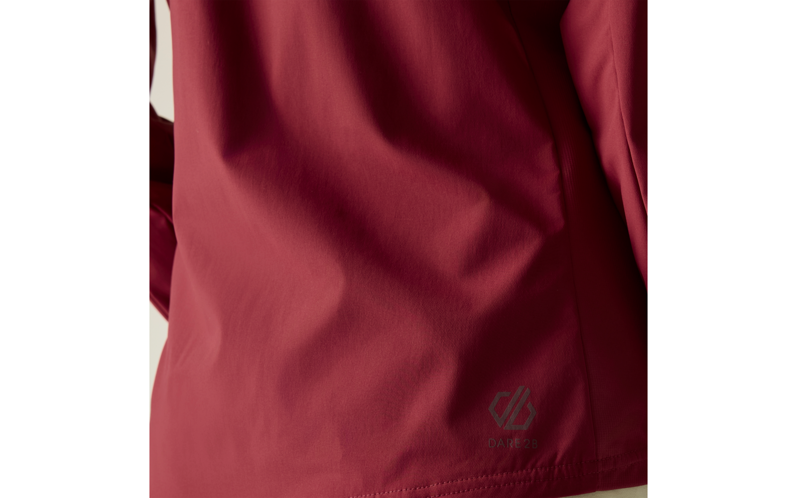 Close-up van iemands rug in een rood jack, zichtbare mouw en klein reflecterend merklogo bij de onderzoom