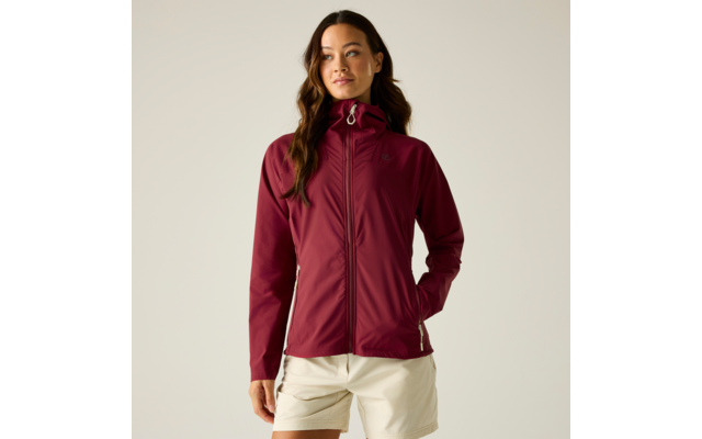 Vrouw met bordeaux capuchonjas (gesloten) en witte korte broek, staand voor een lichte achtergrond, kijkt opzij