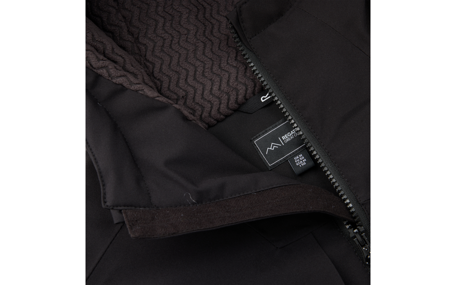 Nahaufnahme einer schwarzen Jacke mit teilweise geöffnetem Reißverschluss, braunem gestricktem Futter, Klettverschluss und Innenetikett