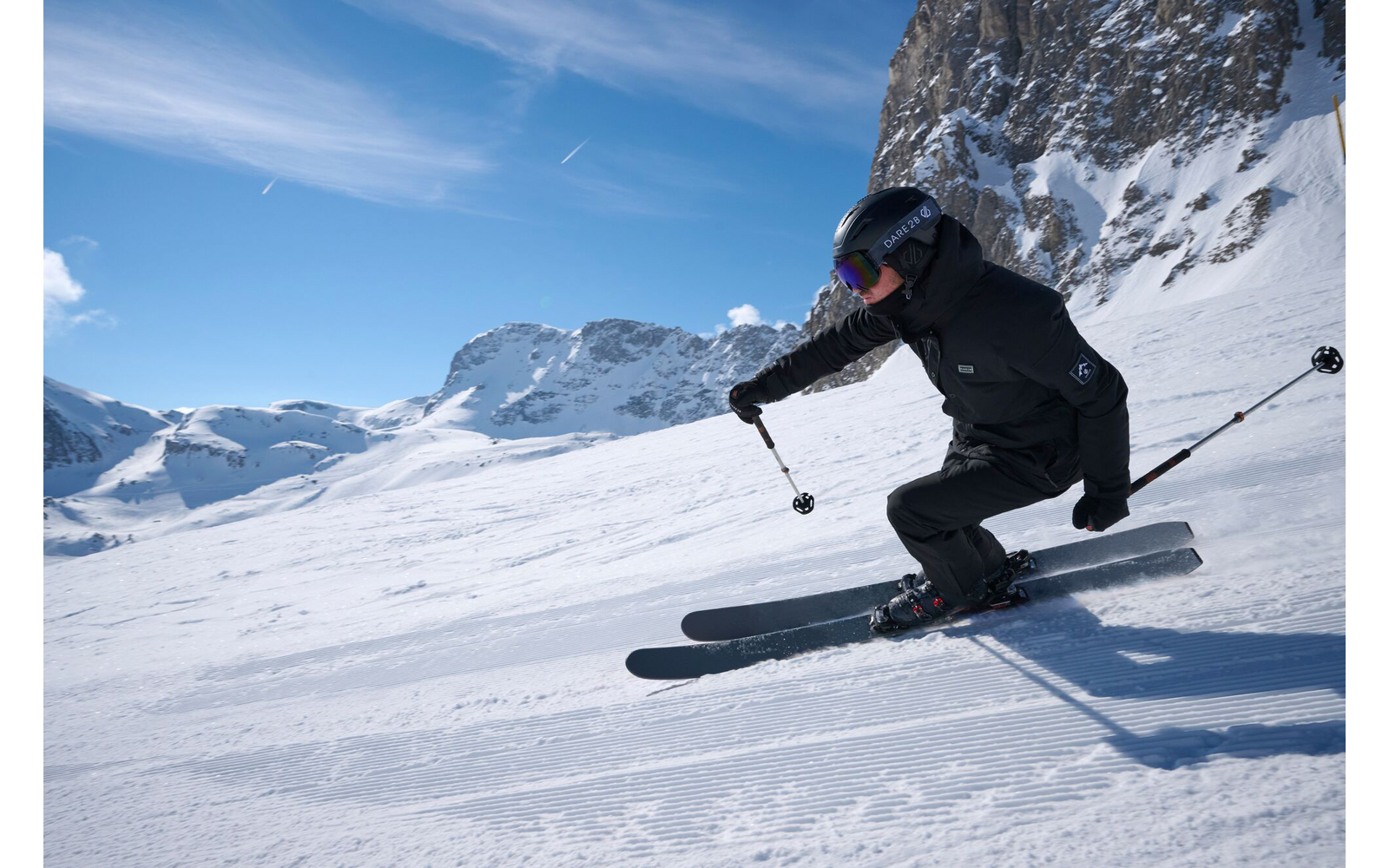 Person fährt Ski in bergiger Schneelandschaft bei Sonnenschein