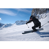 Person fährt Ski in bergiger Schneelandschaft bei Sonnenschein