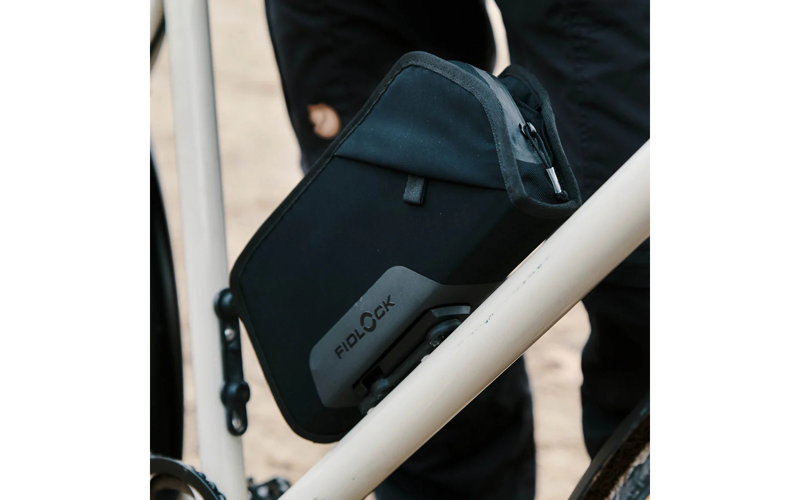 Schwarze Fidlock-Tasche an weißem Fahrradrahmen befestigt
