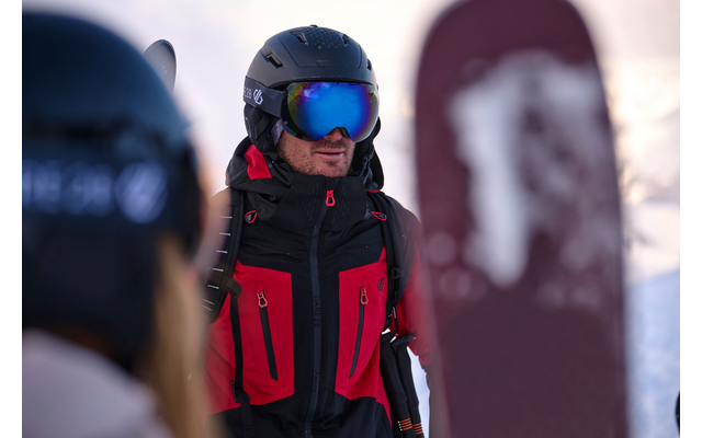 Person in Skibekleidung und Helm mit Skibrille im Schnee