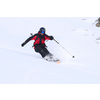 Person fährt Ski im Schnee mit roter Jacke und blauem Helm