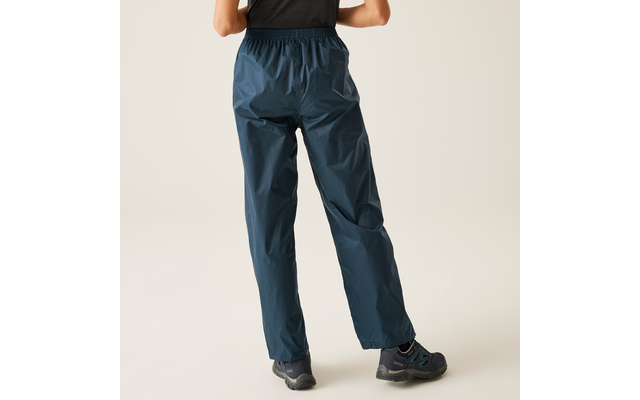 Rear view of a person from the waist down wearing dark blue rain pants and dark hiking shoes on a light background