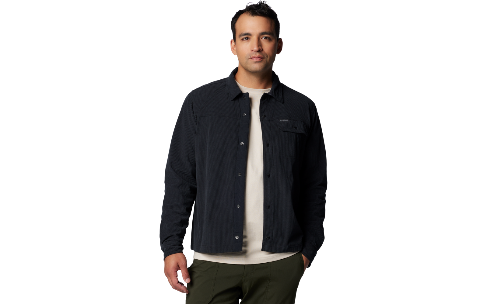 Staande man kijkt in de camera, draagt een zwarte overshirt over een wit T-shirt en een olijfgroene broek voor een witte achtergrond