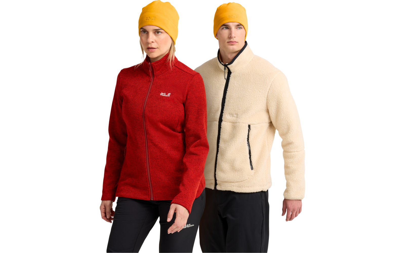 Zwei Personen stehend; links Frau in roter Fleecejacke, schwarzer Hose und gelber Mütze; rechts Mann in cremefarbener Fleecejacke mit schwarzem Reißverschluss und Taschen, schwarzer Hose und gelber Mütze