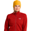 Frau mit gelber Mütze und roter Jacke mit Reißverschluss und weißem Logo, Blick nach rechts