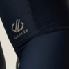 Plano detalle de tejido elástico azul oscuro con costuras visibles y el logotipo blanco 'DARE2B'