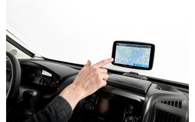 Hand zeigt auf Navigationsgerät mit Kartenansicht auf dem Armaturenbrett eines Fahrzeugs