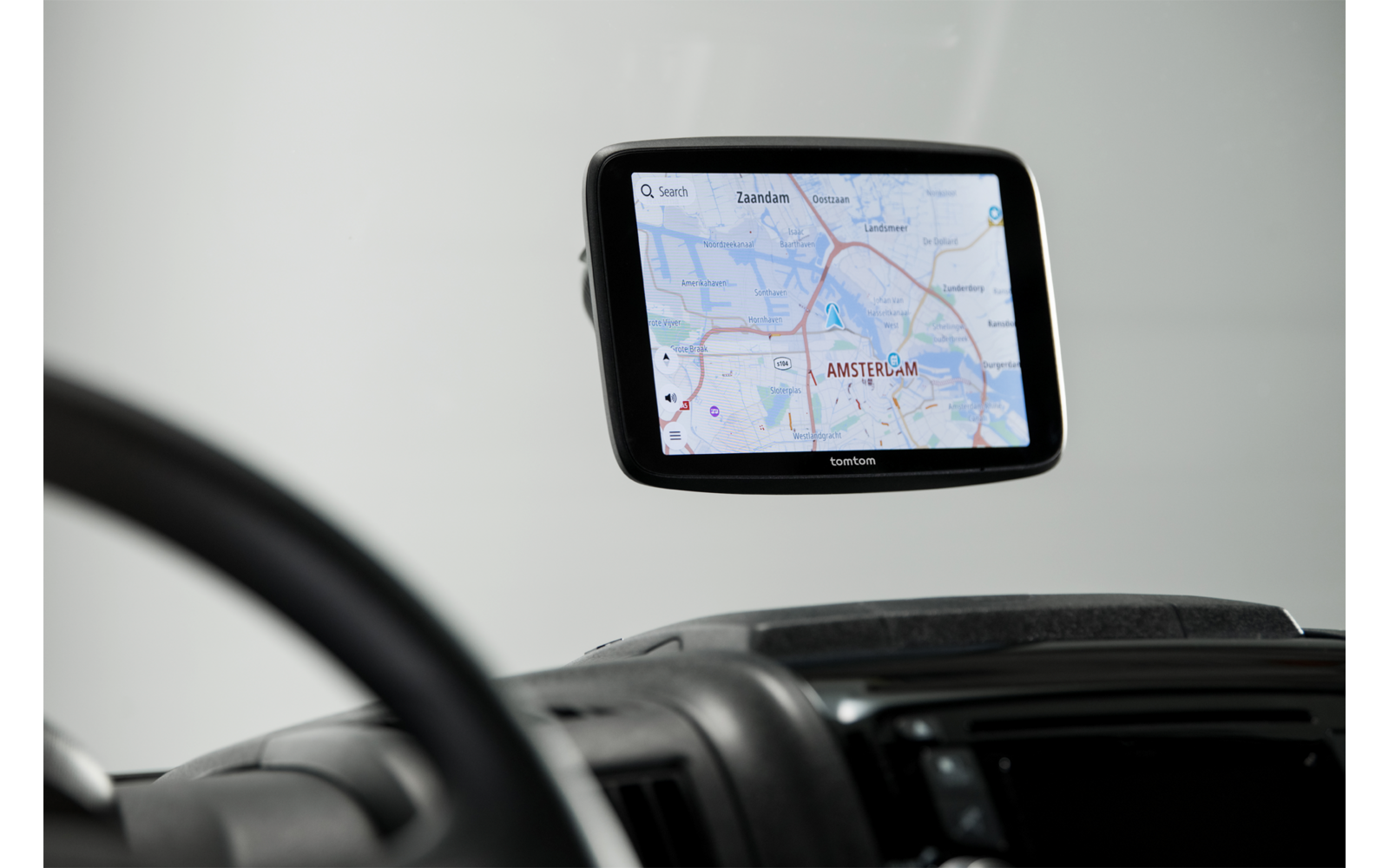 Navigationsgerät mit Kartenansicht von Amsterdam an der Windschutzscheibe, im Vordergrund Armaturenbrett und Lenkrad
