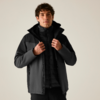 Person mit dunkler Softshelljacke und gesteppter Innenjacke, Hände am Reißverschluss, heller einfarbiger Hintergrund