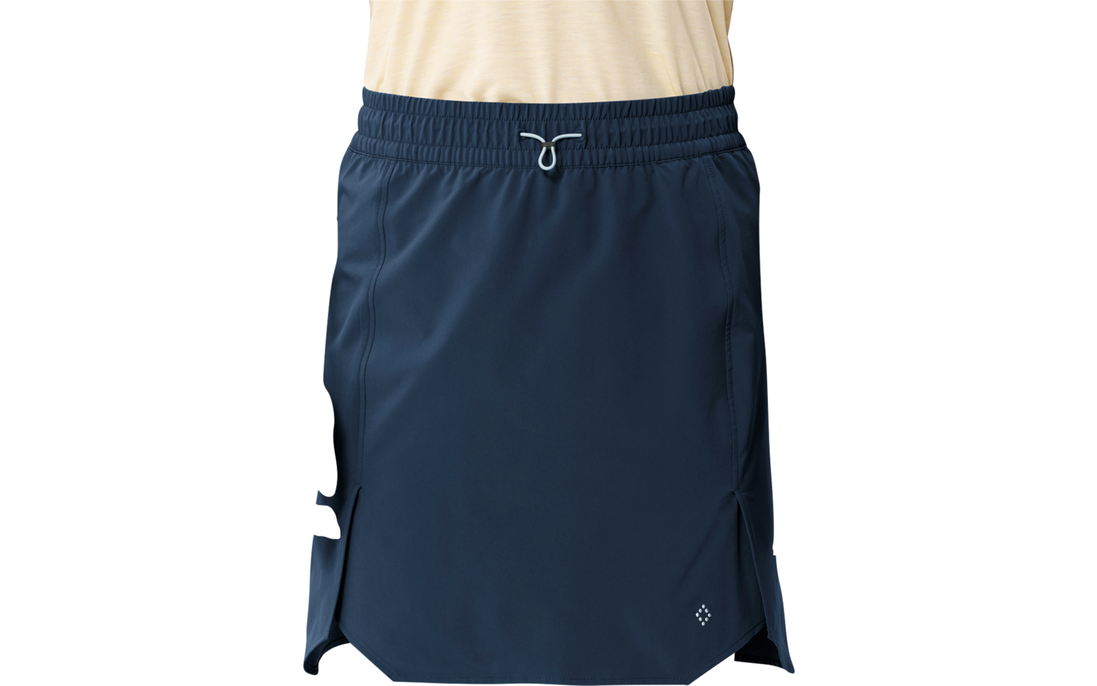 Personne de la taille aux pieds portant une jupe bleu marine à taille élastique et cordon, fentes latérales, petit logo à l'avant, chaussettes différentes (gauche noire, droite grise) et chaussures noires à lacets