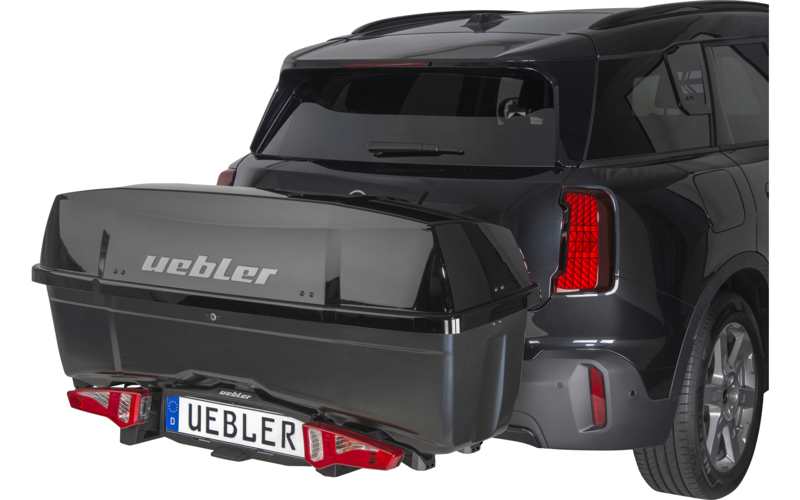 Retro di un SUV nero con un baule nero montato sul gancio di traino, scritta uebler e targa visibile