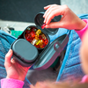 Mains tenant une boîte bento grise sur les genoux ; un compartiment ouvert montre des oursons en gelée colorés